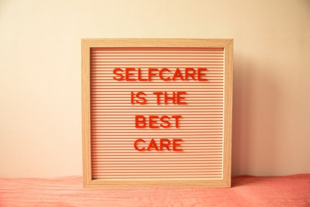 A wooden letter board with red text reading "SELFCARE IS THE BEST CARE"