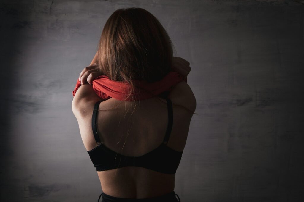 Woman in black bra removing red shirt