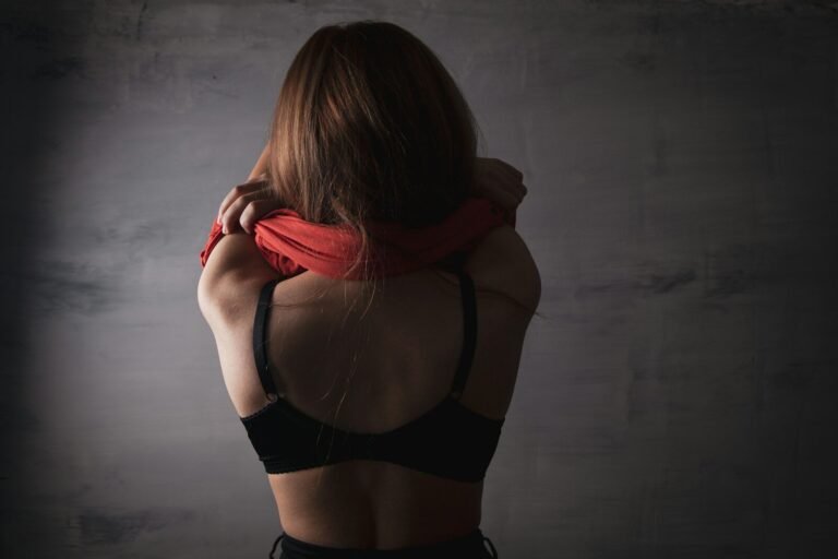 Woman in black bra removing red shirt