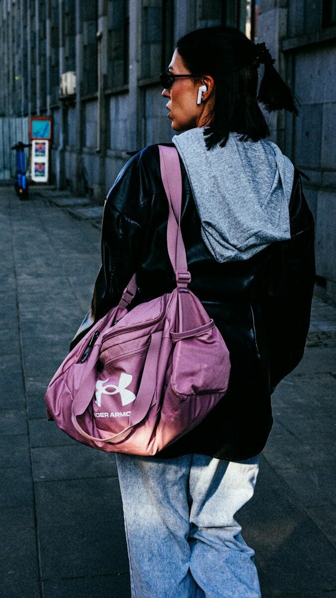 Woman with pink duffel bag walking on sidewalk